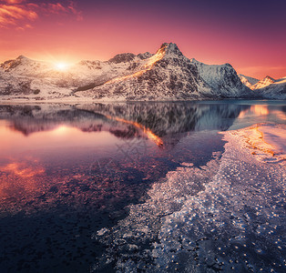 雪山的鸟瞰,蓝色的大海霜冻的海岸,挪威洛福滕岛五颜六色的日落时,水紫色的天空中反射冬天的风景雪覆盖的岩石,峡湾冰背景图片