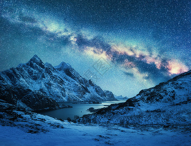 雪上的银河覆盖了挪威冬天的山脉海岸风景雪岩,蓝色的星空,五颜六色的星系,美丽的峡湾挪威洛福腾群岛背景图片