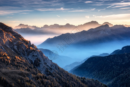 意大利白云石秋天美丽的日落时,雾中的山脉景观与高山山谷,低云,树木山上,村庄雾,蓝天与云空中视野帕索贾乌背景图片