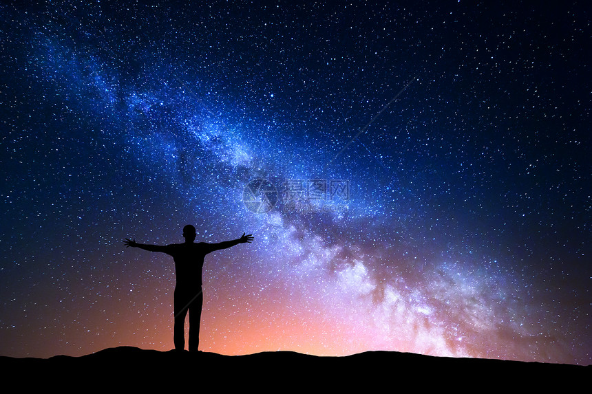 银河的夜晚景观个站着的轻人山上举手臂的剪影美丽的宇宙旅行背景与蓝色夜空星空图片