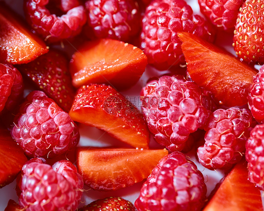 天然新鲜采摘的水果红色背景与覆盆子草莓特写顶部视图由成熟的覆盆子草莓片制成的天然机背景的特写图片