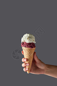 个红色的水果球个香草白色的冰淇淋球,个华夫饼锥,由个女人的手灰色的背景下夏季与华夫饼锥与红色樱桃背景图片