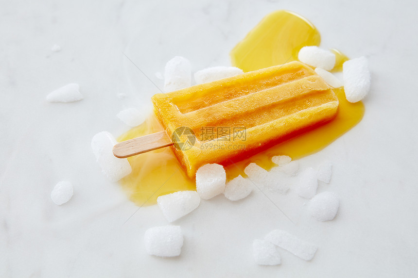 橙色融化的冰淇淋与冰片灰色大理石桌子上与的副本夏天甜点的平躺橙色水果冰淇淋棍子上,灰色大理石背景上冰片图片