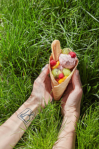 个女人手里,个华夫饼锥,水果饼干覆盆子,背景青草华夫饼锥里的浆果冰淇淋图片