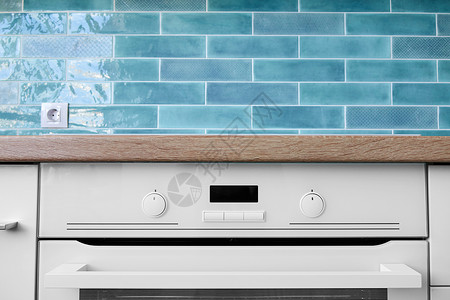 白色烤箱,背景为棕色台蓝色瓷砖新的现代白色烤箱与器图片