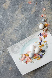 白色的春天鸡蛋,石头背景上花复活节彩蛋配花装饰图片