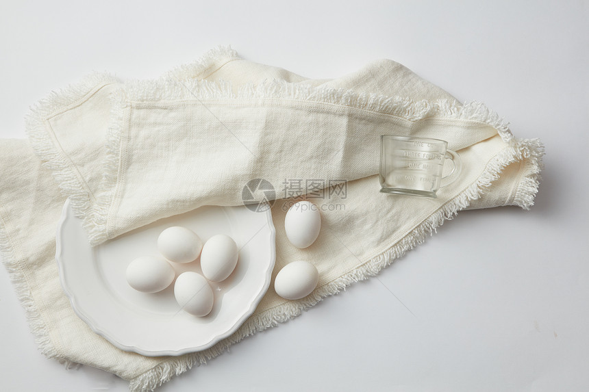 白色桌子上餐巾上的盘子里生鸡蛋的顶部视图生鸡蛋图片