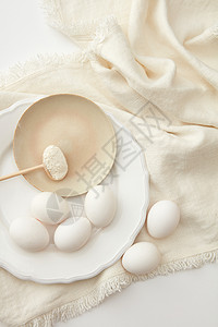 新鲜鸡蛋与粉米色餐巾上的白色背景粉加鸡蛋图片