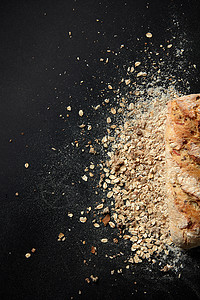 新鲜的小麦包,种子粉上,薄片黑色的背景上,平躺着新鲜的自制包背景图片