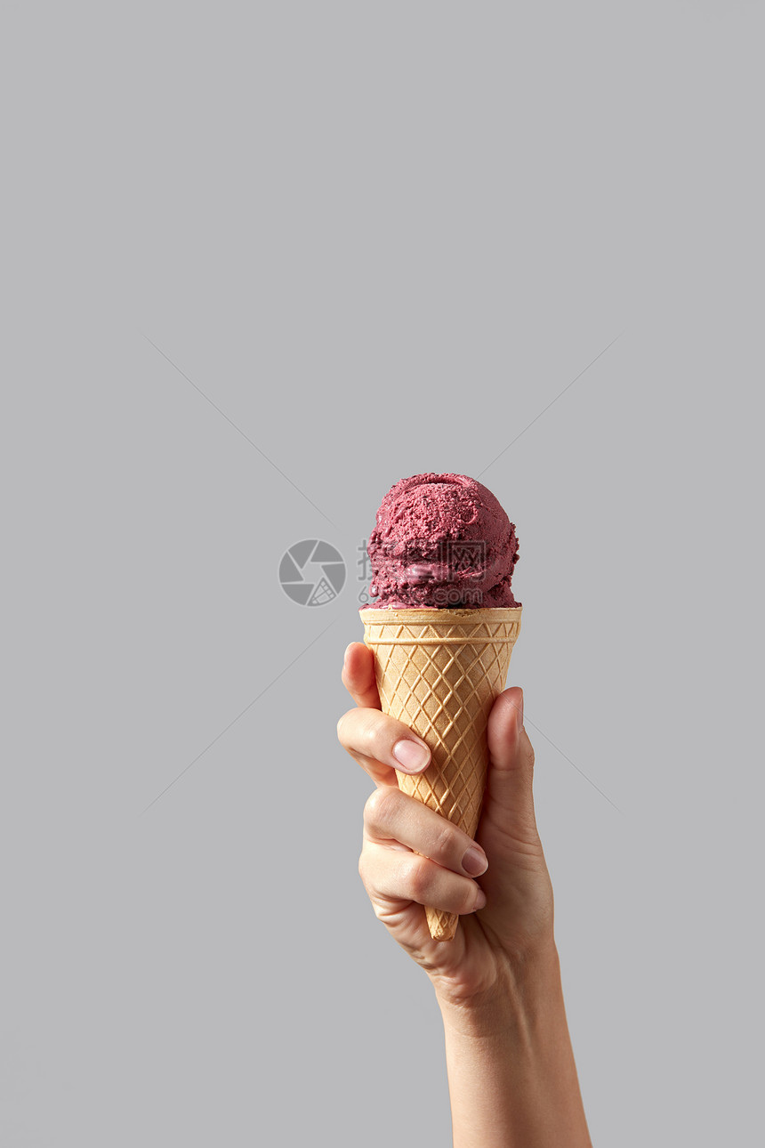 浆果红色冰淇淋的形式,华夫饼锥个家庭的手灰色的背景夏季与文字个女人的手着个华夫饼锥与红色樱桃山梨浅图片