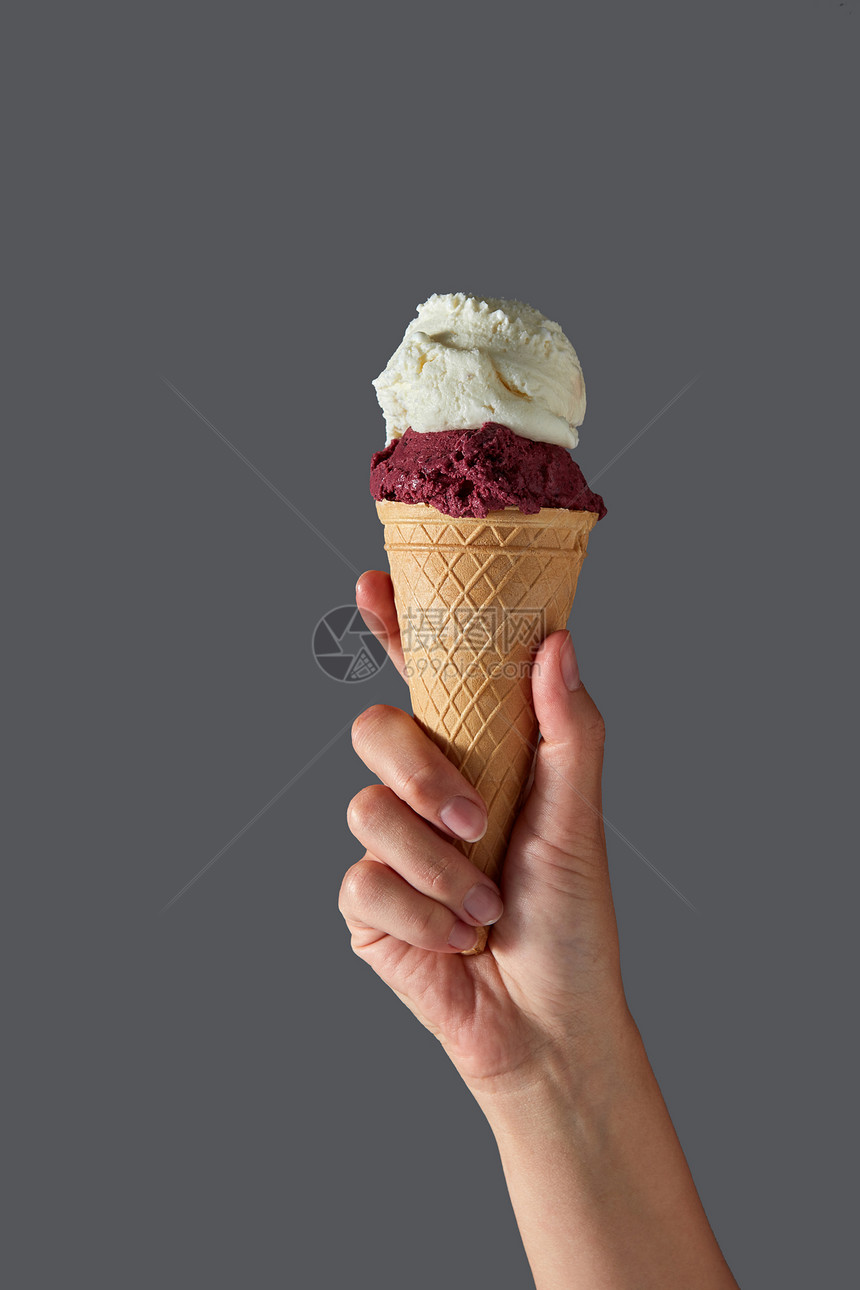 只雌的手着灰色背景上的华夫饼锥中的红色浆果冰淇淋白色牛奶冰淇淋夏季与红色水果山梨糖香草冰淇淋的形式,图片