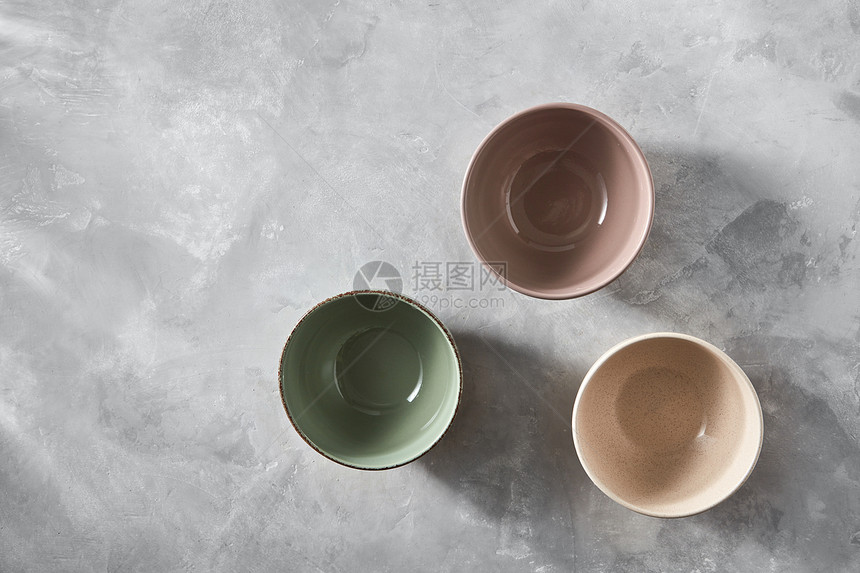 三个彩色瓷器手工陶碗孤立石灰色背景与,平躺三个五颜六色的瓷碗孤立石灰色的背景上,平躺着图片
