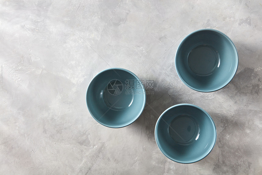 三个蓝色瓷碗隔离石灰色背景上,平躺三个蓝色手工制作的中国碗灰色的石头背景平躺图片