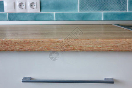 白色厨房家具的部分,棕色的桌靠蓝色的瓷砖上白色厨房家具的部分图片