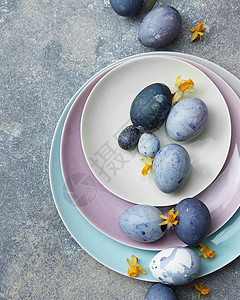 复活节蓝色鸡蛋个彩色的餐盘上,石头背景上花蓝色复活节彩蛋背景