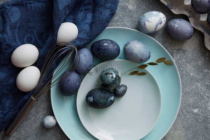 复活节鸡蛋盘子上,布绿色植物石头背景上用蓝布烤复活节彩蛋图片