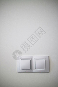 混凝土墙上的双白色照明开关,电源插座插头与切换混凝土墙上的电动两个白色照明开关背景图片