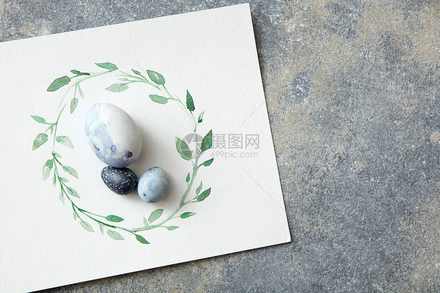 蓝色复活节彩蛋纸上与水彩框架石头背景复活节鸡蛋与手绘树叶纸上图片