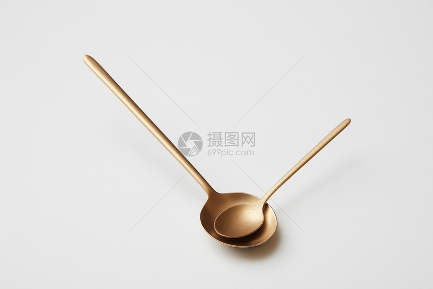 大而小的金属金匙隔离灰色背景上吃饭的时候,勺子以箭头的形式放手表上大而小的勺子被隔离灰色的背景上图片