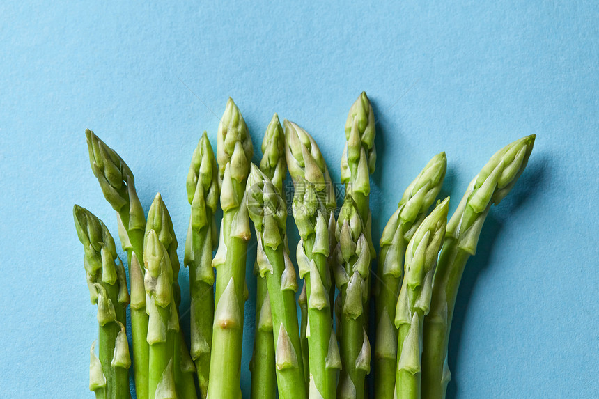 堆新鲜的芦笋蓝色上分离出来健康素食平躺绿色芦笋视图正的纹理图片
