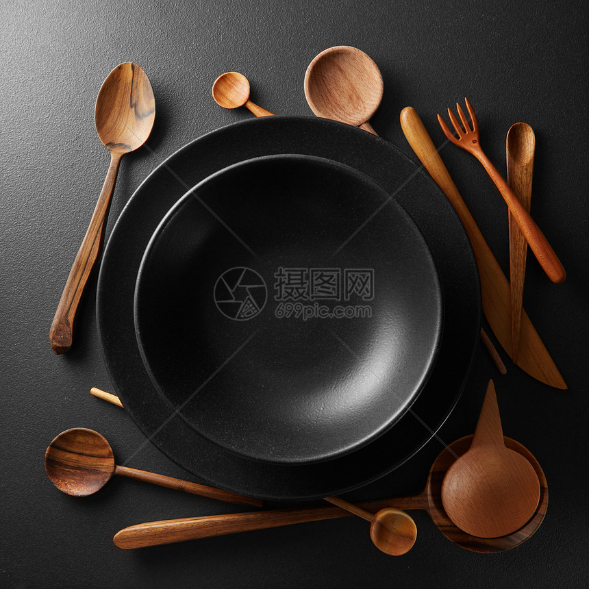 黑色桌子上的黑色盘子木勺子叉子刀盘子木制餐具图片