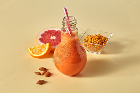 水果饮料蔬菜新鲜冰沙与胡萝卜,橙色,葡萄柚,杏仁沙棘个璃纸橙色背景维生素饮料的橙色冰沙与柑橘,胡萝卜,沙棘杏仁橙色的纸背景