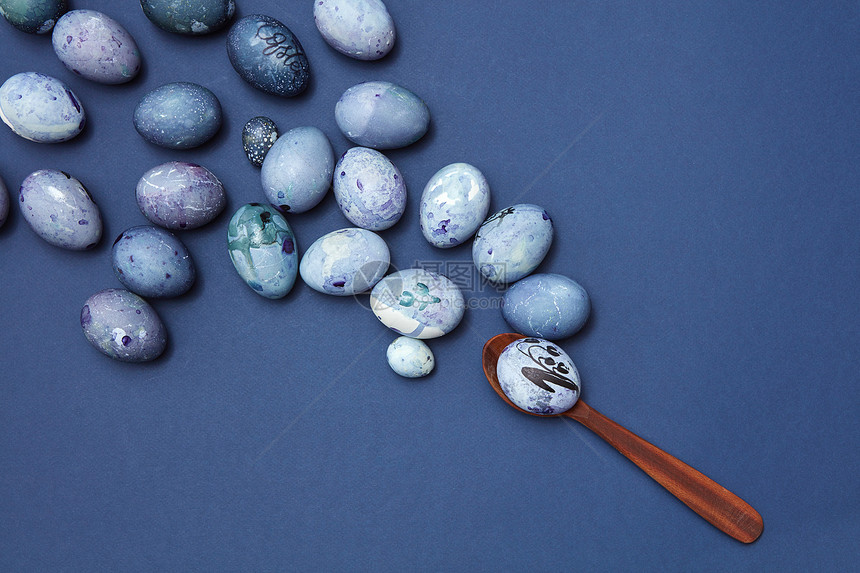 复活节鸡蛋木制勺子蓝色背景,平躺五颜六色的复活节彩蛋图片