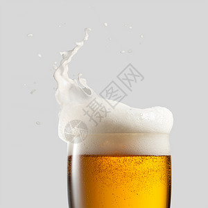 特写冷啤酒与泡沫飞溅灰色背景用泡沫封闭冷啤酒图片