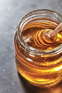 甜花天然蜂蜜罐子里,木勺灰色的混凝土桌子上罗什哈沙纳犹太新假期木制北斗七星个璃瓶与芳香的天然蜂蜜灰色的混背景图片