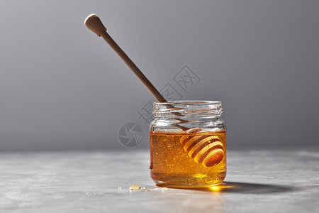 甜花天然蜂蜜罐子木勺上灰色大理石桌子,犹太罗什哈沙纳假日芳香的新鲜机蜂蜜,灰色的石桌上的璃壶里放着迪背景图片
