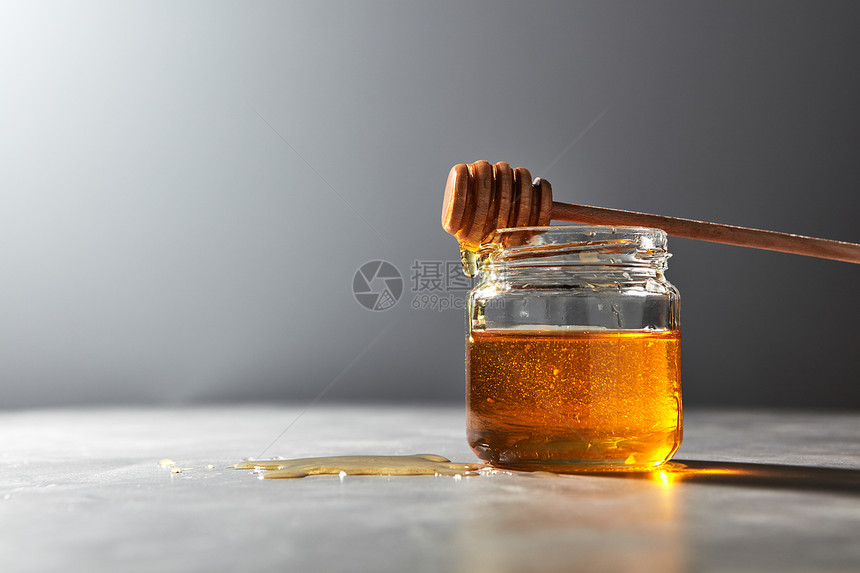 芬芳的天然机蜂蜜木制迪普滴入灰色厨房大理石桌子,放置文字罗什哈沙纳犹太新健康假日木制蜂蜜勺子个璃瓶上,装满图片
