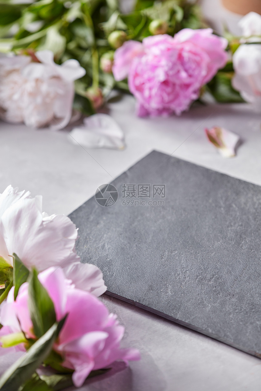 花瓣花的粉红色牡丹灰色的混凝土背景与黑色石板板的明信片石板板装饰花瓣粉红色的牡丹花灰色的混凝土背景图片