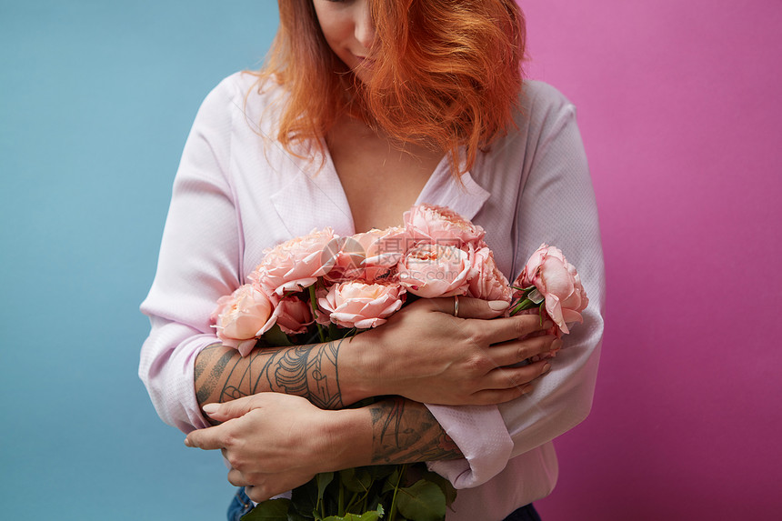粉红色玫瑰的花个轻的女人手中,纹身个双玫瑰的蓝色背景与母亲节美丽的红发女人,纹身粉红色的花个双图片