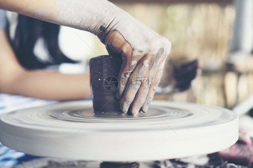 女人的手靠近,熟练的陶瓷工作室用粘土陶工的车轮上工作图片
