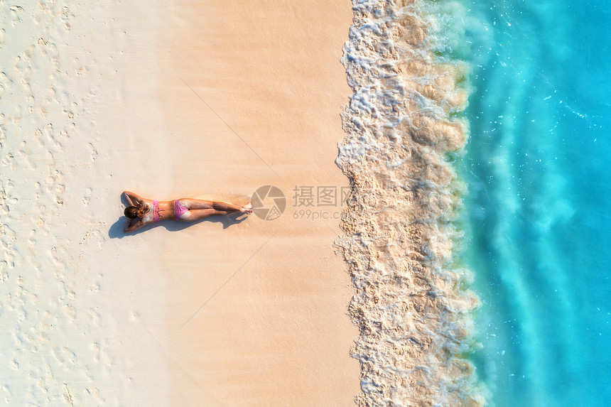 鸟瞰美丽的轻女人躺白色的沙滩上,靠近大海,日落时波浪暑假顶部的背运动苗条的女孩,清澈的蔚蓝的水感的图片