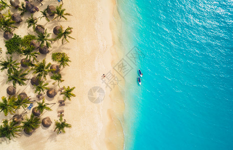 日落时,遮阳伞沙滩上的棕榈树海上的皮艇的鸟瞰图非洲桑给巴尔的暑假热带景观棕榈树,阳伞,船,沙子,碧水的风景背景图片