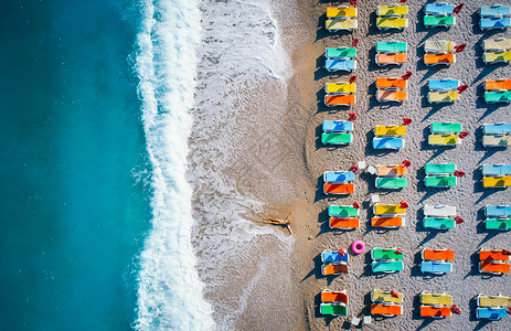 美丽的轻女人太阳升奥卢德尼斯,土耳其鸟瞰躺海滩上的女人与五颜六色的躺椅无人机的顶部视图海景与女孩,蔚蓝的水背景