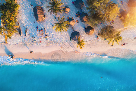 日落时,印度洋的沙滩上俯瞰雨伞棕榈树非洲桑给巴尔的夏季旅行热带景观棕榈树,阳伞,人,沙子,碧水,海浪的风景背景图片