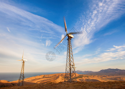 工业景观与风力涡轮机发电山区日落图片