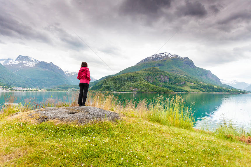 旅行成熟的旅游妇女海边看峡湾美丽的风景,奥登村,挪威峡湾县女游客峡湾海岸,挪威放松图片