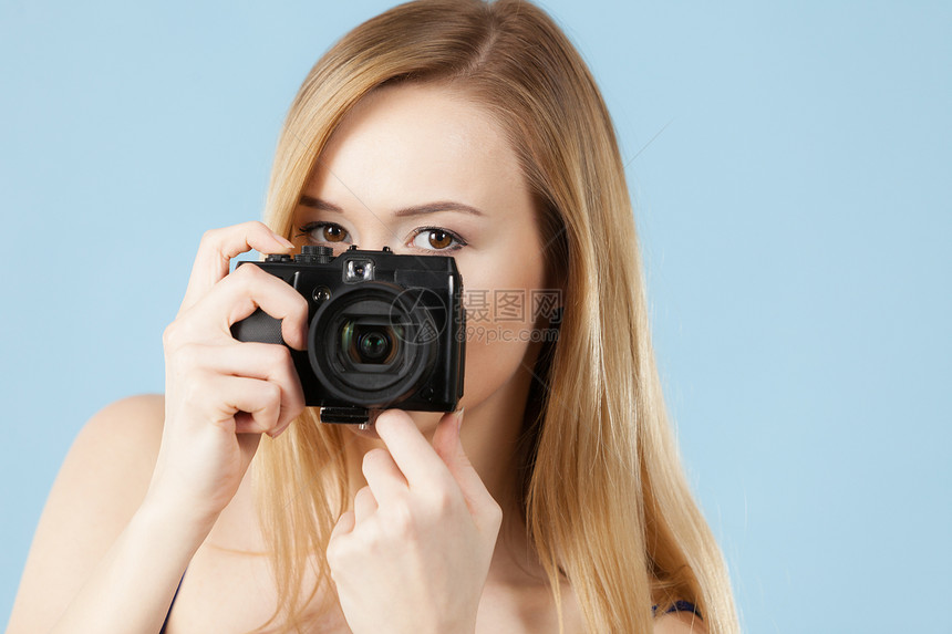 摄影师女孩拍摄图像可爱的金发微笑的女人,蓝色背景上照相机戴着蓝色相机的金发女人图片
