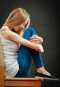 孤独消极情绪轻的悲伤的孤独的女人蜷缩椅子上图片
