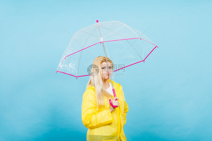 悲伤无聊的金发女人穿着黄色雨衣,着透明的雨伞等雨悲伤无聊的女人穿着雨衣,着雨伞图片