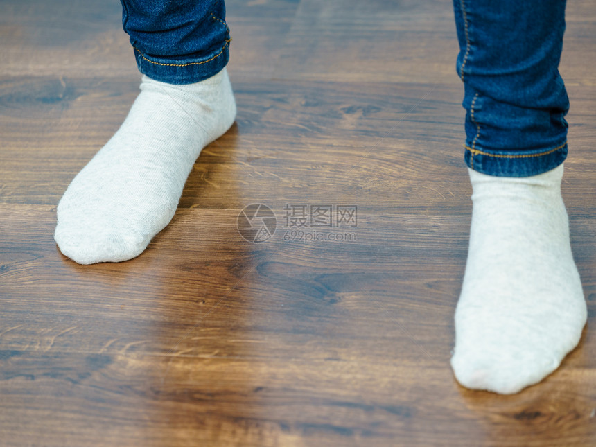 女人的脚站木地板上,穿着蓝色牛仔裤浅色袜子穿袜子的女人认出来图片