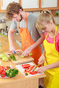 健康饮食,素食,烹饪,减肥人的快乐的轻夫妇厨房里准备新鲜蔬菜沙拉餐图片