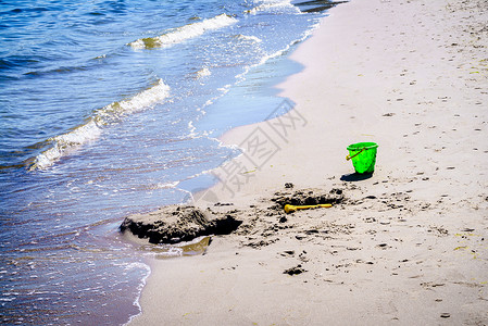 个孩子沙滩上留下的绿色玩具桶人海边的沙子里玩绿色玩具桶海滩上图片