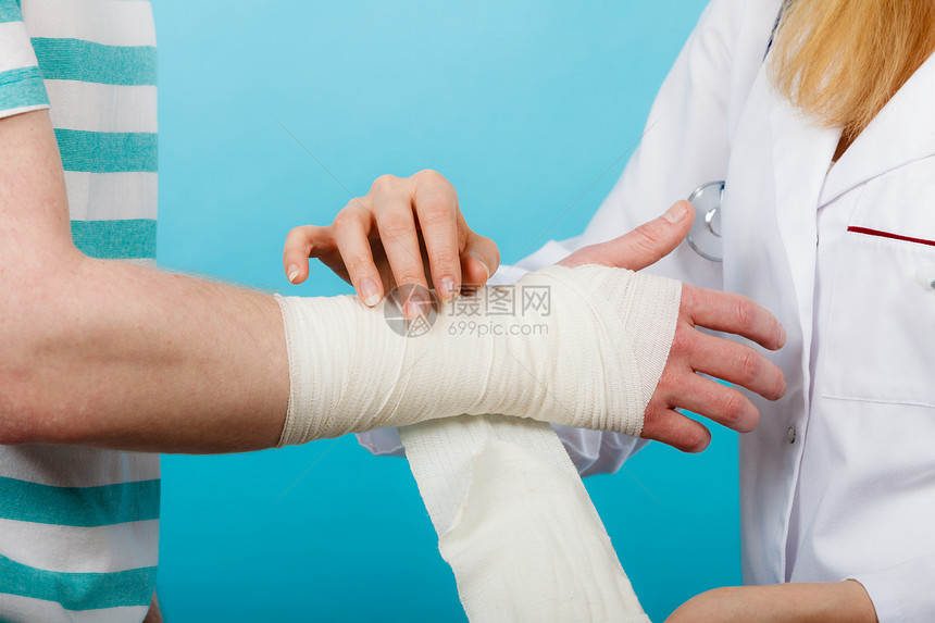 医学医疗保健女医生包扎男手扭伤手腕拜访医学专业人士的轻人医生包扎扭伤了手腕图片