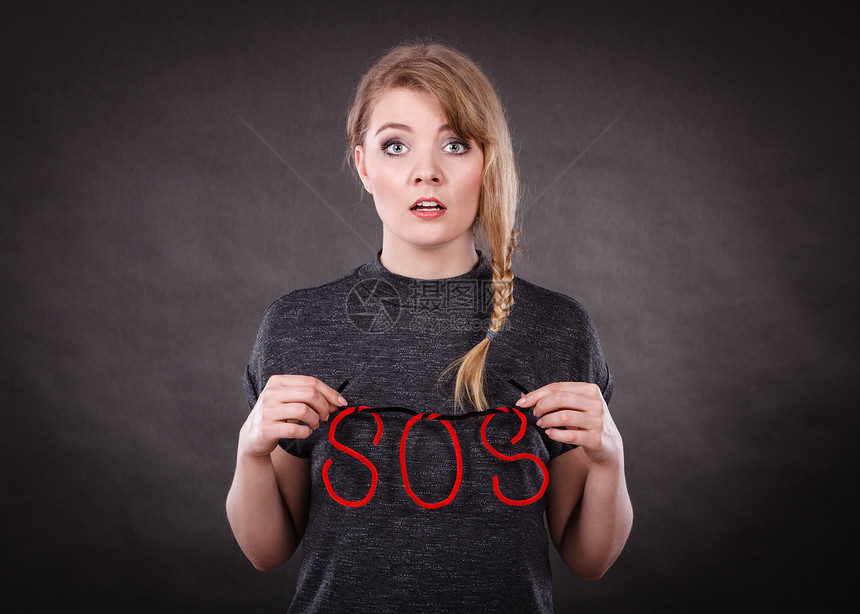 惧惧轻的金发吓坏了的女人需要帮助受惊吓的绝望的女,黑暗的背景上红色的SOS标志符号受惊吓的女人用SOS帮图片