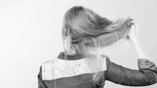 发型发型理发的背的金发女人玩直长发发型师理发师毛求疵金发女人玩弄头发图片
