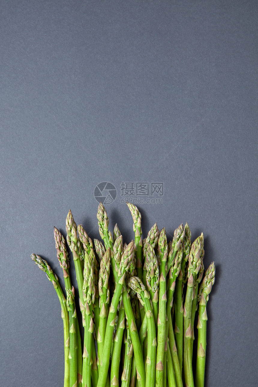 新鲜的生芦笋,用于灰色背景下烹饪素食,并的风景纯素健康营养灰色背景上的新鲜天然芦笋堆图片